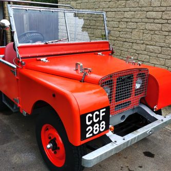 Red early Land Rover with hand painted number plates